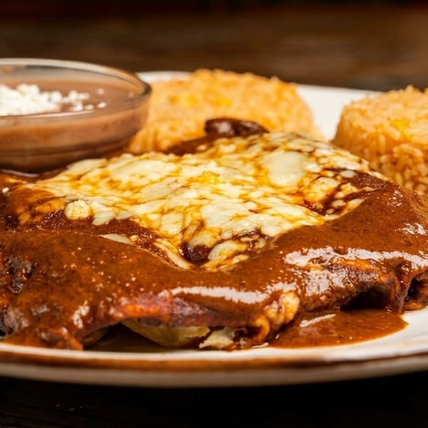 Enchiladas with rich mole sauce and melted cheese, served with rice and refried beans.